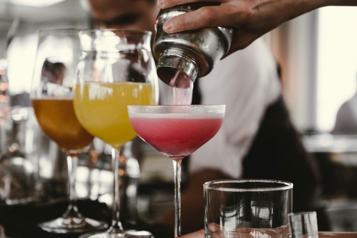 A mixologist making a pink cocktail