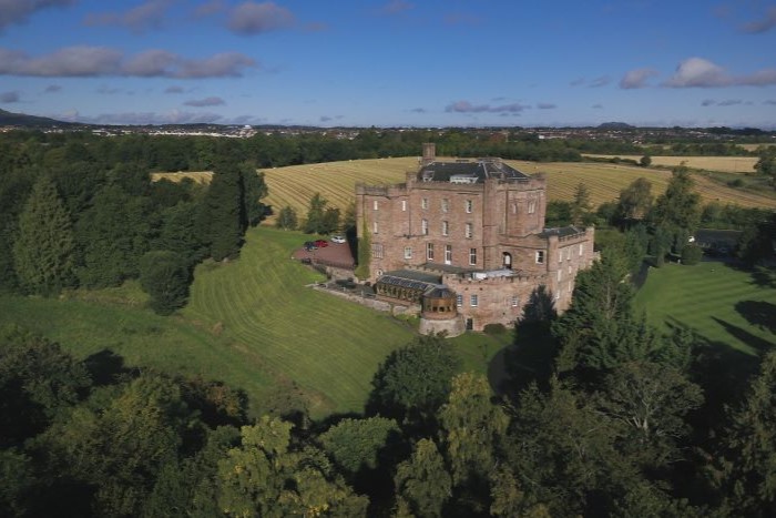 Aerial view of Dalhousie Castle in Edinburgh, with green fields and woodland surrounding the grand castle.