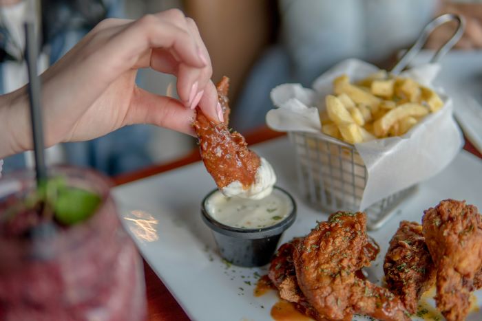 Woman dipping chicken into sauce