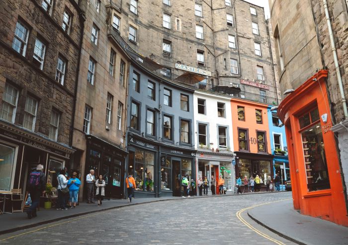 Looking up Victoria Street in Edinburgh lined with colourful shops and people.