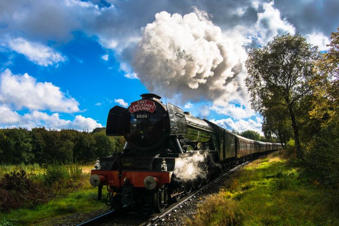 Flying Scotsman travels along a viaduct bridge in the Yorkshire Dales, with steam trailing from the engine.