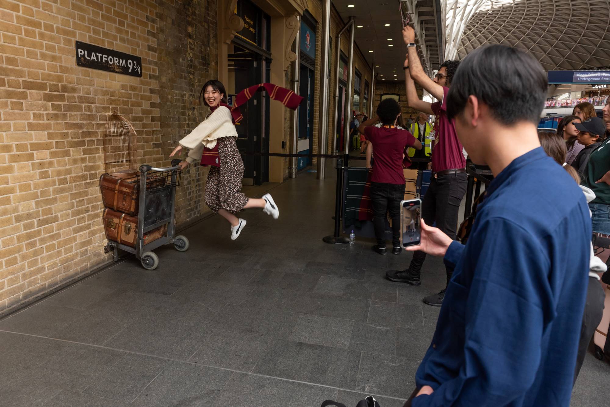 Harry Potter fans taking a photo at Kings Cross platform 9 3/4