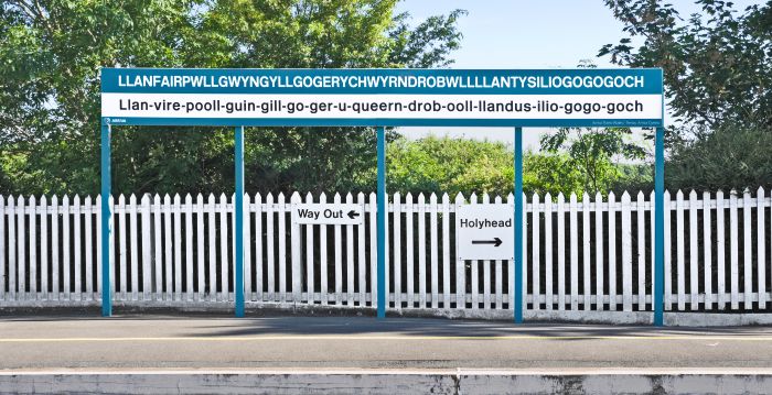 A blue and white sign at a station with the longest train station name on it.