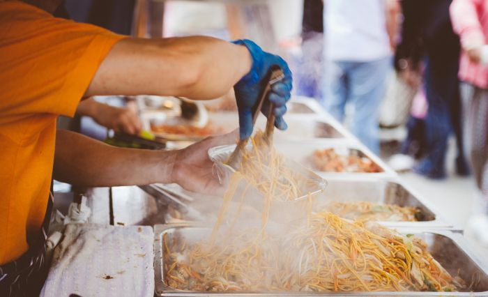 A person serving food at a food stall stand