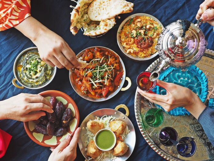 Meal spread with curry, rice, naan, dates, samosas, and tea on a silver tray.