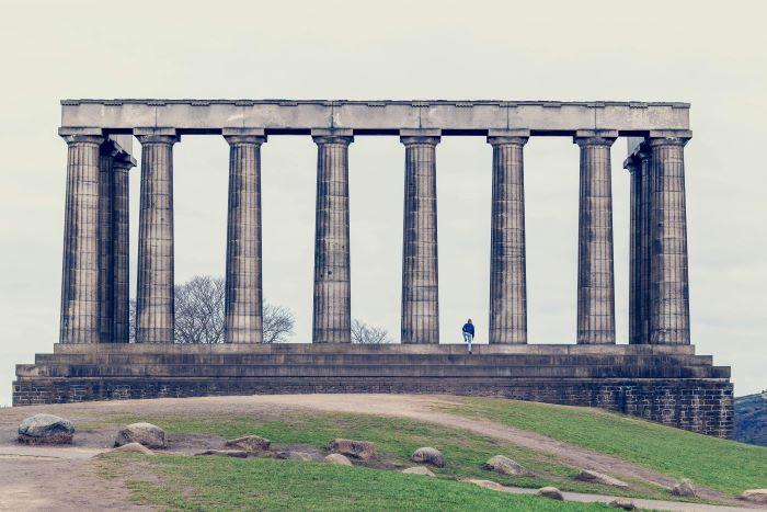 The National Monument of Scotland on Calton Hill with a person climbing its steps.