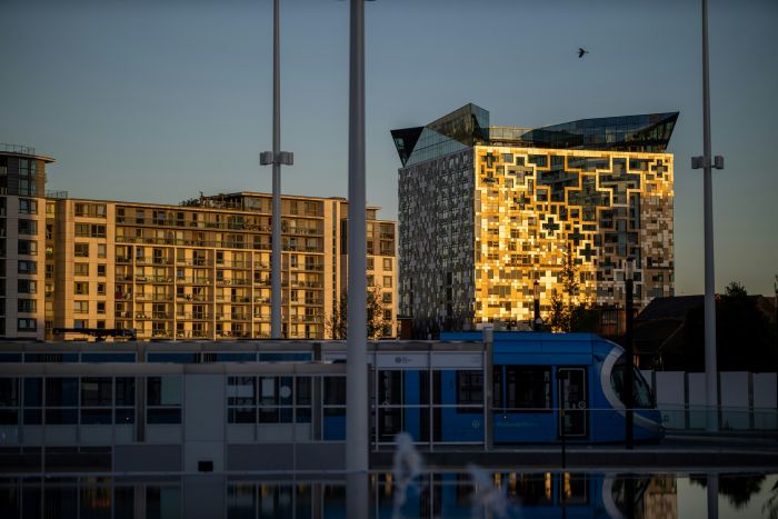 The Cube in Birmingham at sunset, with a tram passing in the foreground.