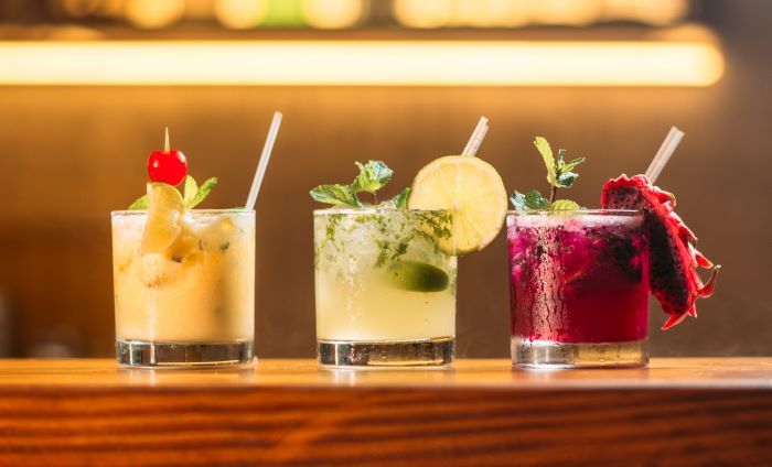 Three colourful cocktails, with cherry, lime and dragonfruit.
