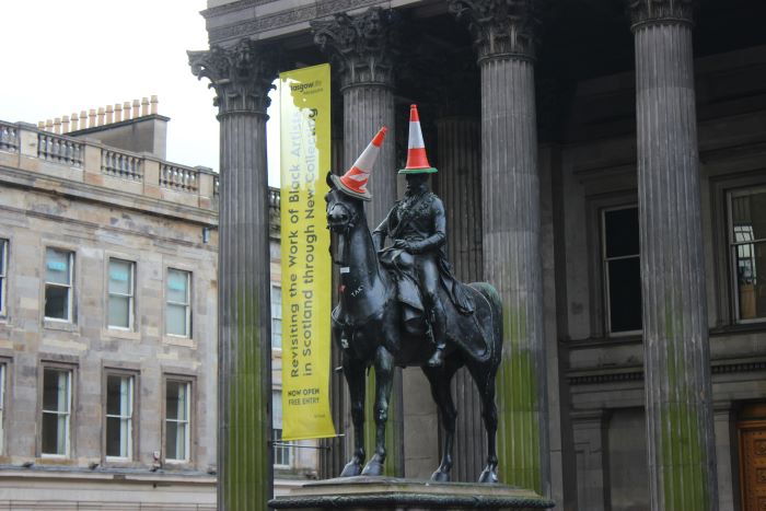 Statue of Arthur Wellesley on horse with a traffic cone on each of their heads. Pictured in front of the Gallery of Modern Art.