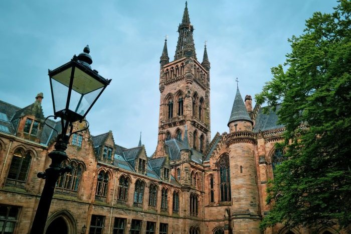 University of Glasgow with a lamppost and tree in the foreground.