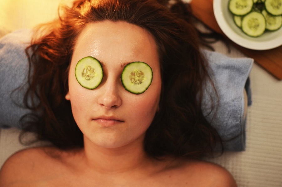 A woman with cucumber on her eyes receiving a treatment