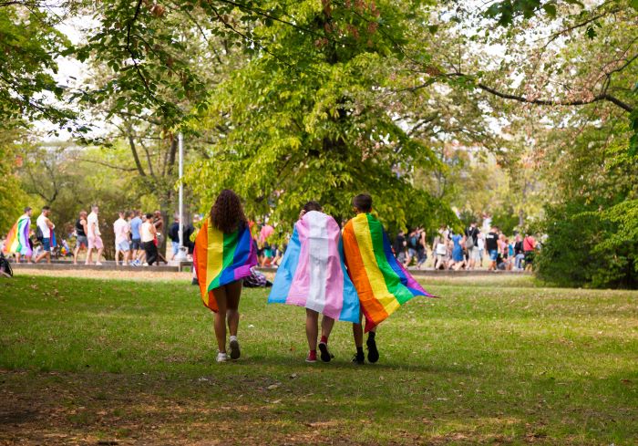 Three people walking with different pride flags
